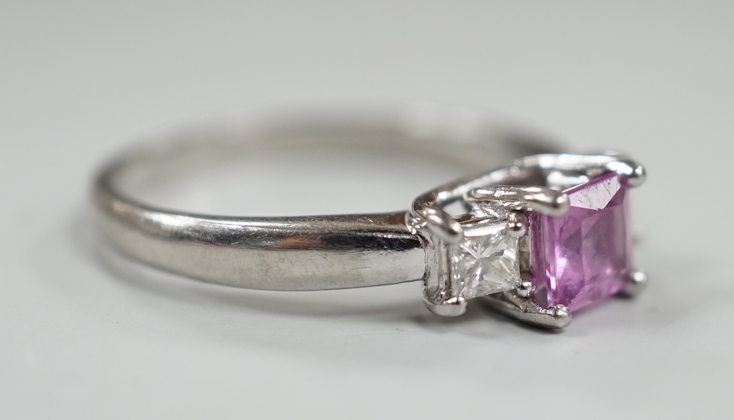 A modern platinum, single stone square cut pink sapphire and two stone diamond set ring, size N/O, gross weight 5.5 grams.